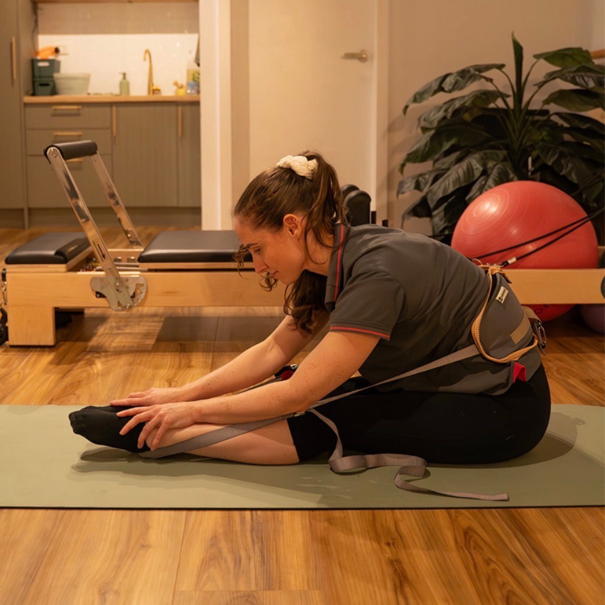 Ustretch adjustable stretching and mobility system used for a seated pike hamstring stretch.